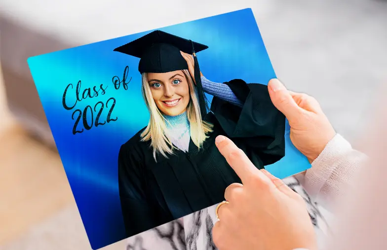 Metalen fotoprint van Printerpix|Aluminium fotoprint van een afstuderen|Kleine vierkante metalen print van een man die in een meer duikt|Metalen fotoprint van moeder en dochter op een boekenplank|Vrouw plaatst metalen print van vriendin en vriend op de muur|Drie metalen fotoprints van verschillende formaten