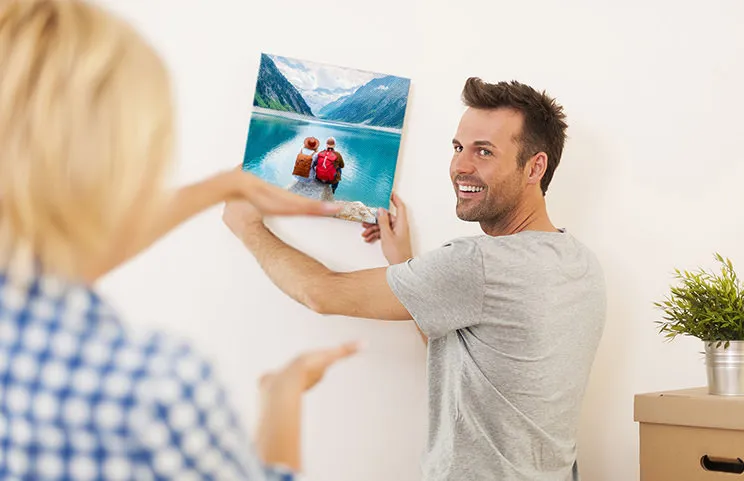 Man en vrouw die een foto canvas ophangen met een vakantiefoto