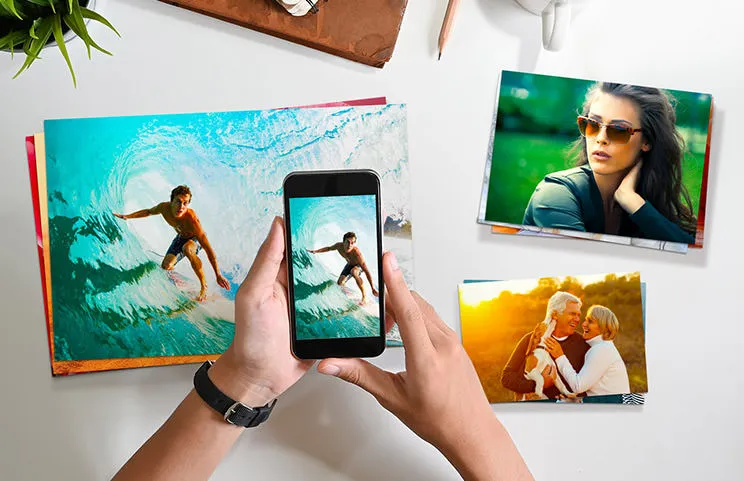 Kleine, middelgrote en grote fotoafdrukken op tafel vanaf mobiele telefoon