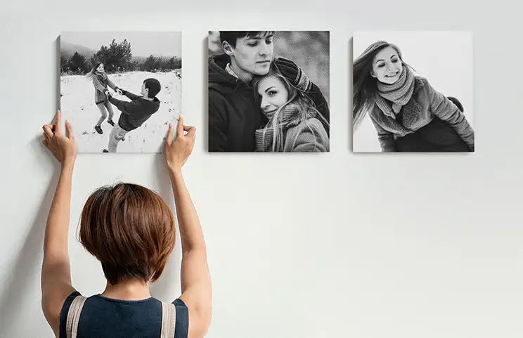 Vrouw die drie zwart-wit familie foto canvasdoeken ophangt