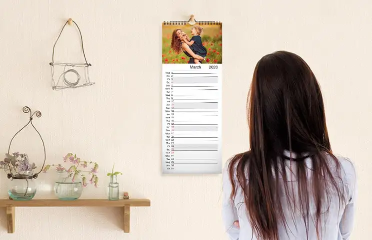 Keukenkalender opgehangen aan de keukenmuur met familievakantiefoto's