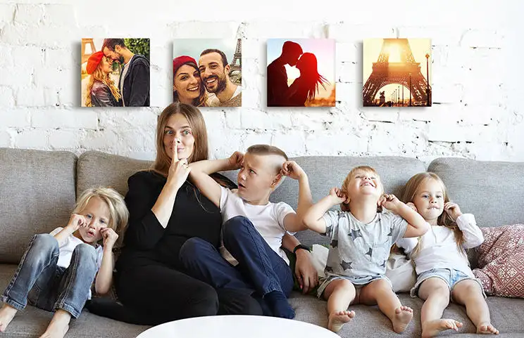 Moeder en vier jonge kinderen zitten op de bank voor vier foto canvasdoeken