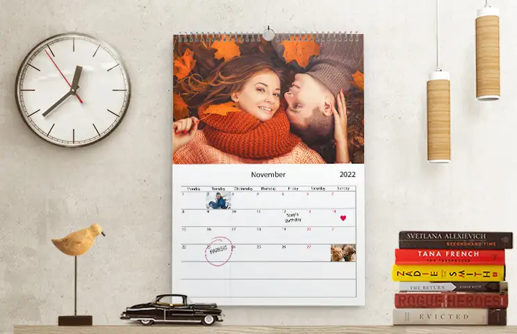 Romantisch stel in de woonkamer met gepersonaliseerde 2020 wandkalender met aanzoekfoto