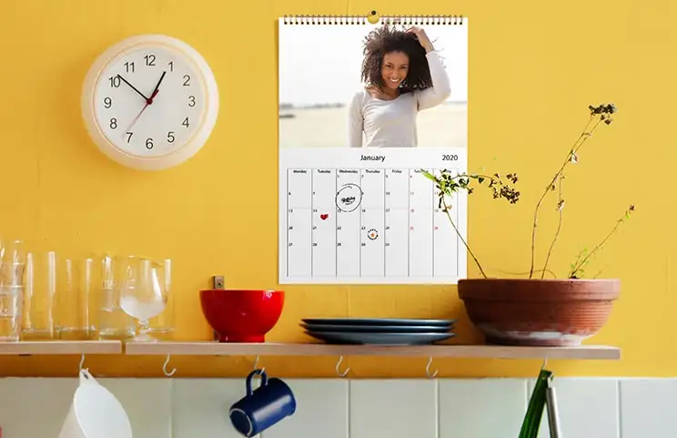 Romantisch stel in woonkamer met gepersonaliseerde 2020 wandkalender met voorstel foto