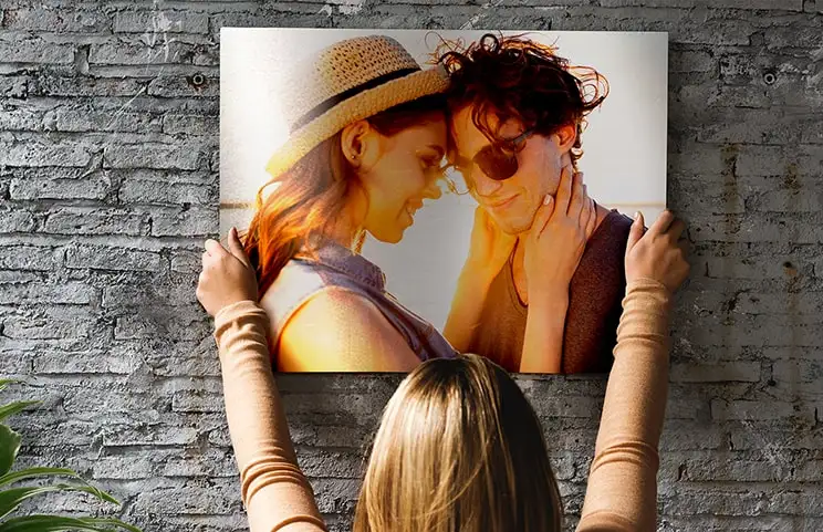Vrouw plaatst metalen print van vriendin en vriend op muur